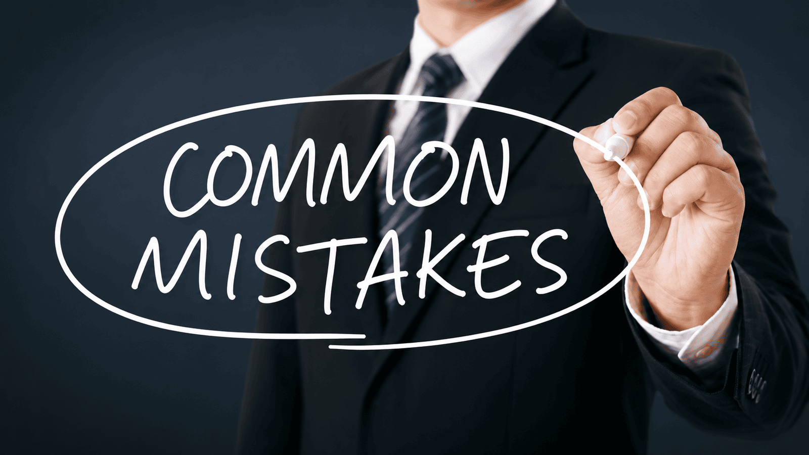 Business professional writing ‘Common Mistakes’ on a transparent surface, representing the operational, financial, and strategic errors that can prevent businesses from adapting effectively to changing market conditions.