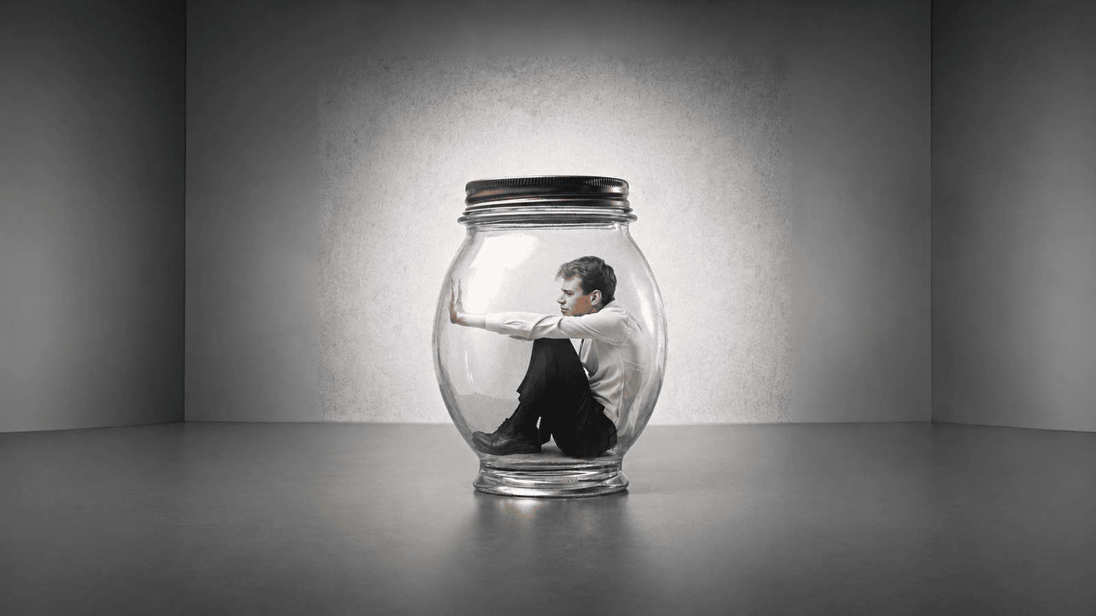 Business owner sitting trapped inside a glass jar, representing the emotional pressure and financial uncertainty entrepreneurs can face when deciding how to pay themselves from their business.