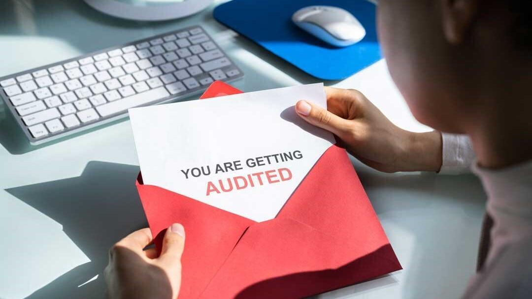 Business owner opening an envelope with ‘You Are Getting Audited’ notice, representing CRA audit types including desk audit, field audit, GST/HST audit, and payroll audit for Canadian small businesses.