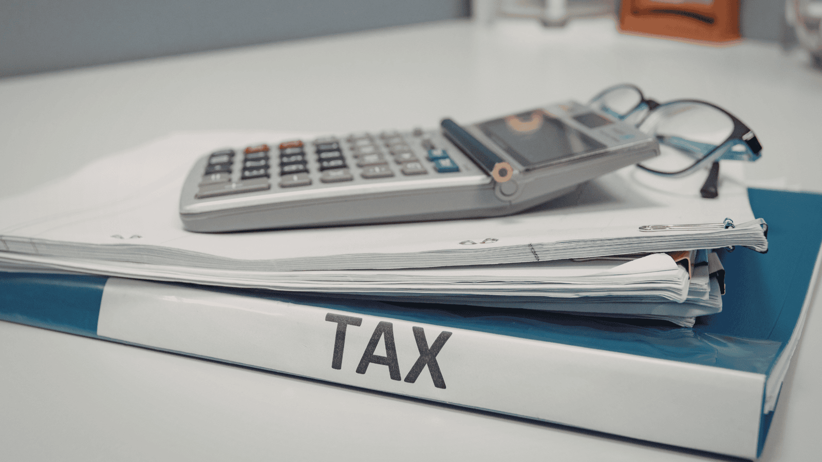 Tax folder, calculator, paperwork, and eyeglasses representing essential income documents such as T4s, T5s, receipts, and records needed for filing 2025 personal taxes in Canada.