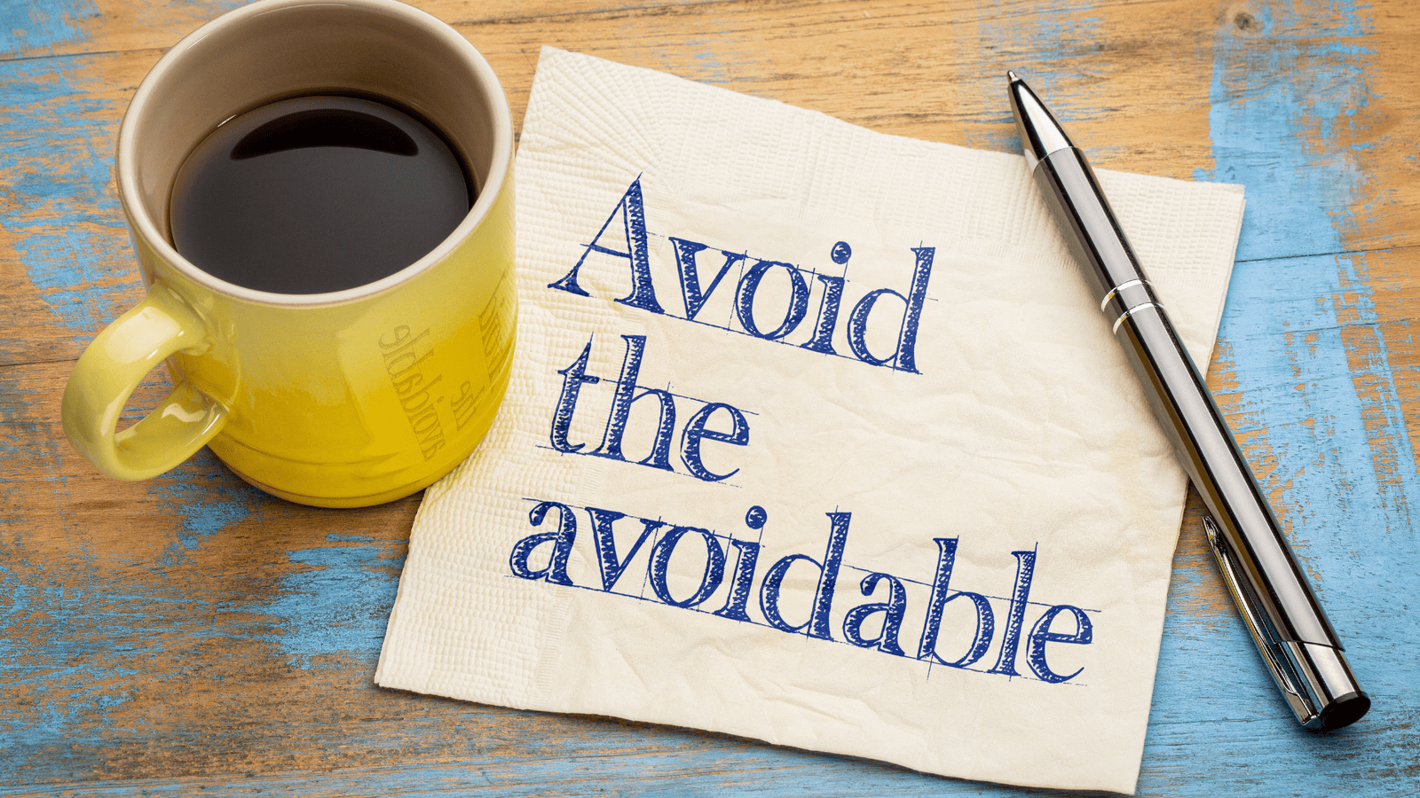 Coffee mug, pen, and note reading ‘Avoid the avoidable’ representing common mistakes to avoid before filing personal taxes, such as missed slips, deadlines, and deductions in Canada.