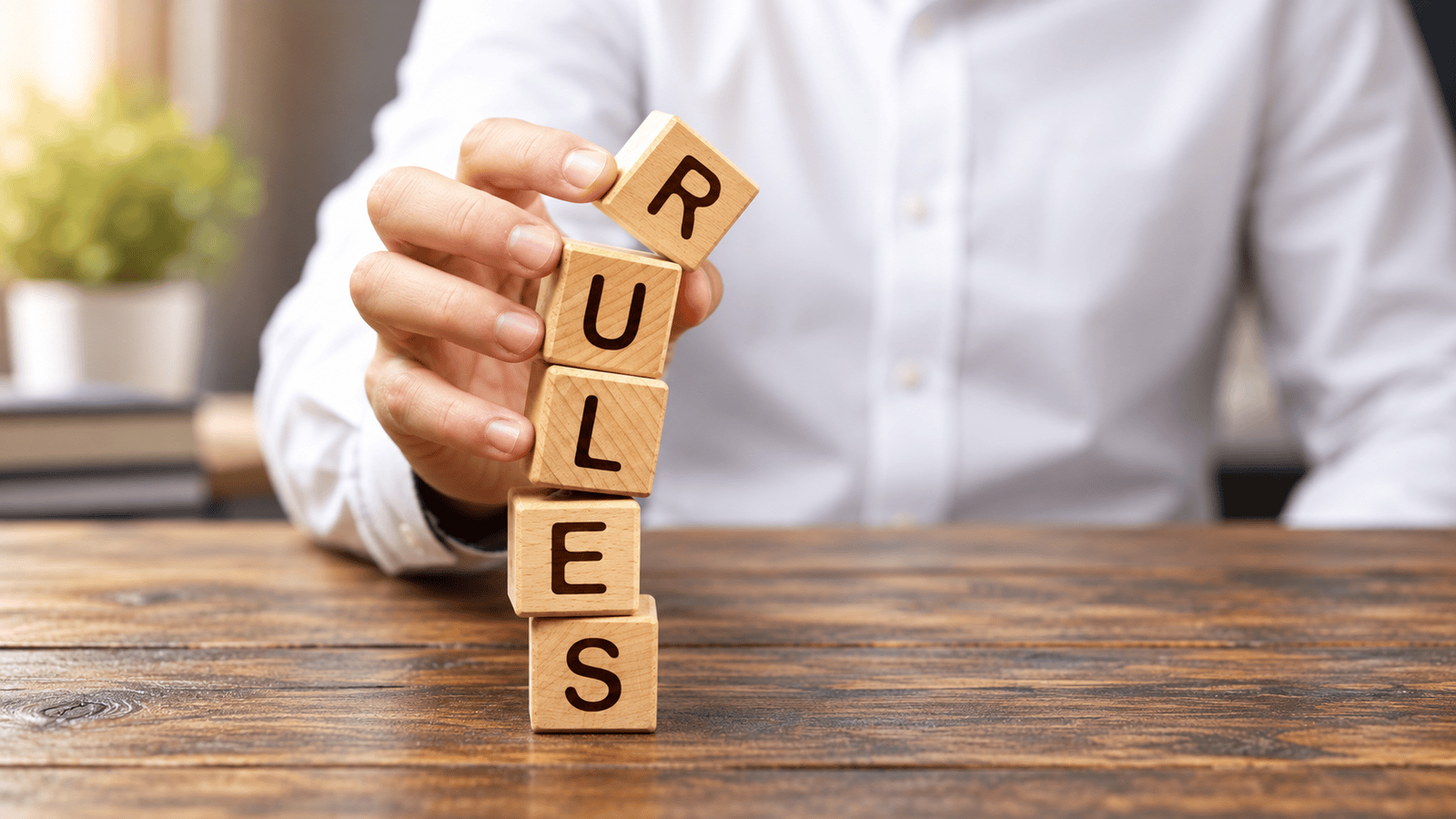 Hand stacking wooden blocks that spell RULES, representing Canadian corporate tax rules that can reduce the small business deduction when passive investment income grows.