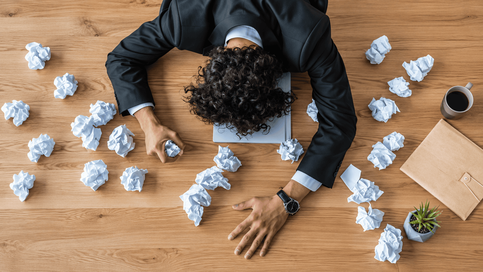 Overhead view of a frustrated business professional surrounded by crumpled paper at a desk, representing confusion, poor systems, and the common onboarding mistakes that make small businesses appear disorganized.