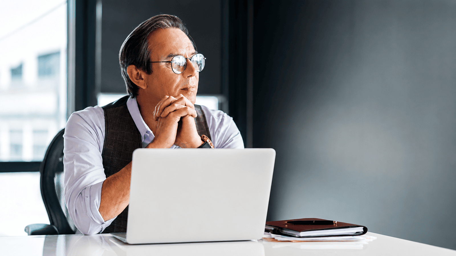 Professional business owner sitting thoughtfully at a desk with a laptop in a modern office, representing the importance of proactive financial management, bookkeeping, and avoiding common mistakes that can increase CRA audit risk.