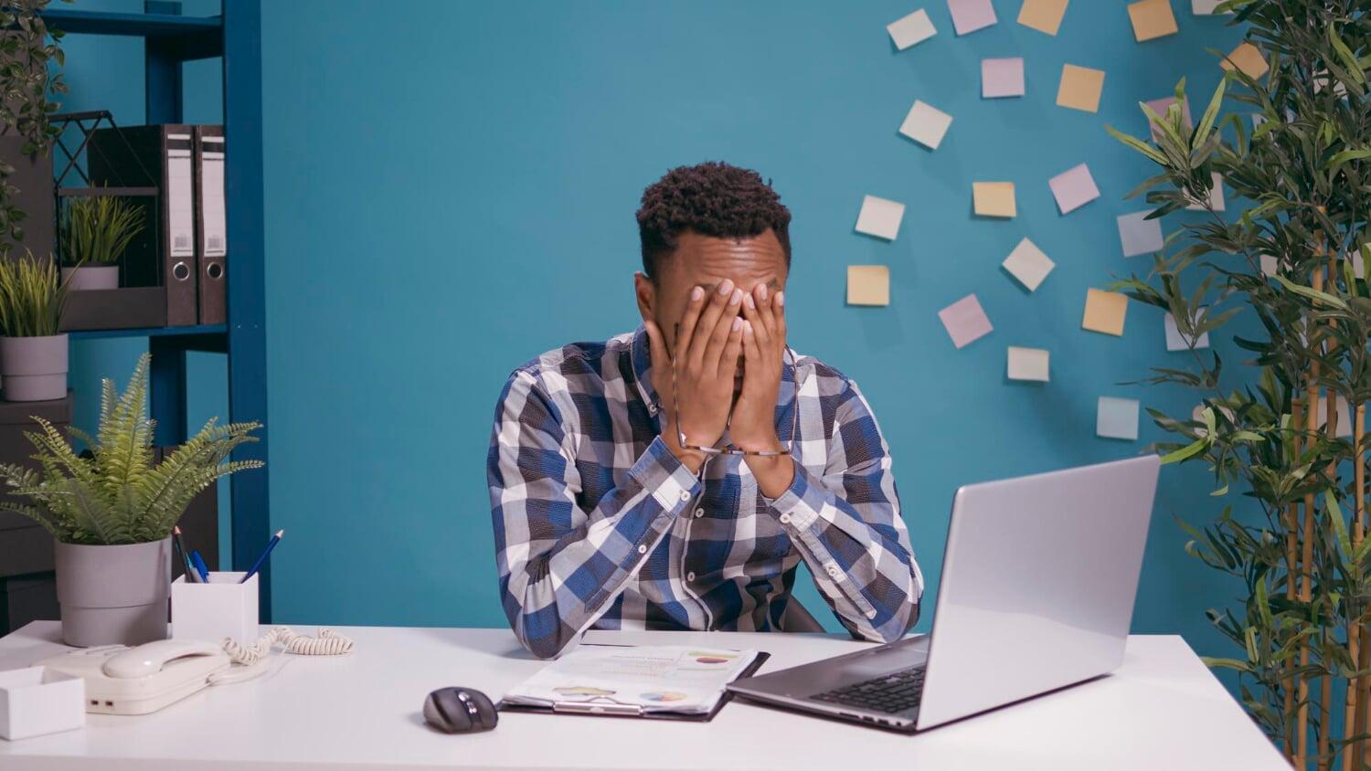 Stressed business owner sitting at a desk with a laptop and financial documents, representing common tax filing mistakes and last-minute errors faced by entrepreneurs in London, Ontario