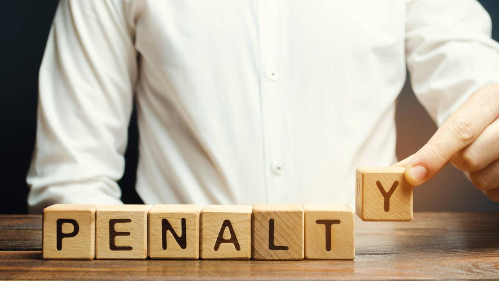 Person placing the final letter “Y” to complete the word “PENALTY” using wooden blocks, representing tax penalties and the importance of avoiding interest charges through timely CRA compliance in London, Ontario.