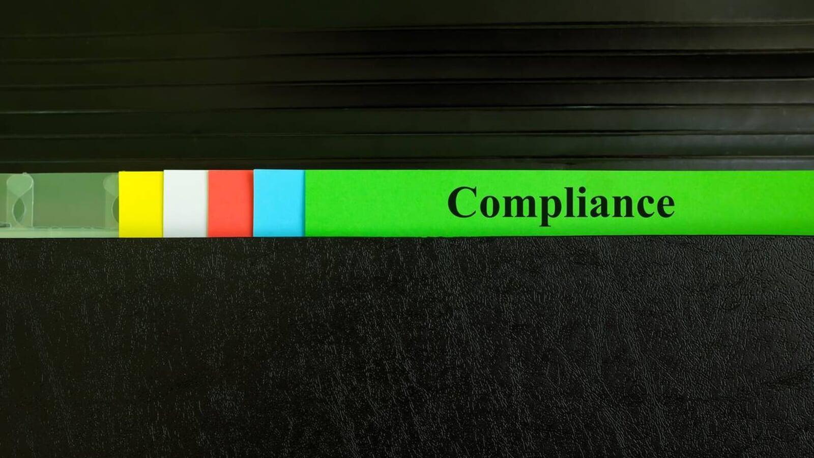 Close-up of a labeled file tab reading “Compliance” with colored dividers in a filing system, representing key CRA filing requirements and organized tax records for small businesses in London, Ontario.
