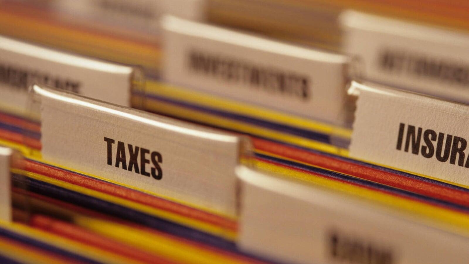 Close-up of organized file folders labeled “Taxes” among other categories, representing important financial documents and records businesses should prepare in advance for CRA tax filing in London, Ontario.