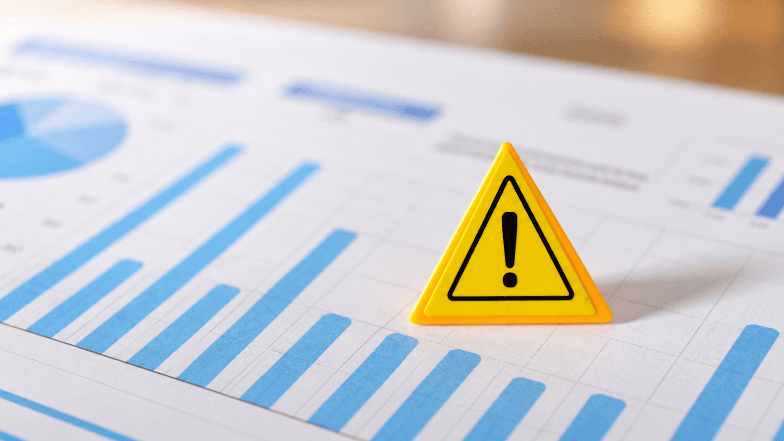Yellow warning sign placed on financial charts, representing key accounting red flags such as outdated bookkeeping, missed GST/HST thresholds, payroll issues, and weak financial reporting for growing businesses in London, Ontario.