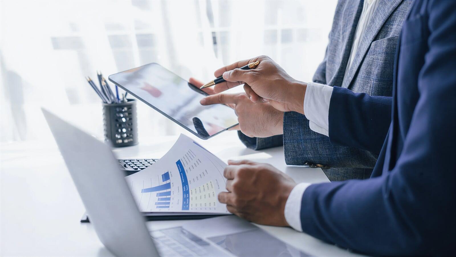 Business professionals reviewing financial documents and a digital tablet beside a laptop, representing the records and information needed before filing taxes for small businesses in London, Ontario.