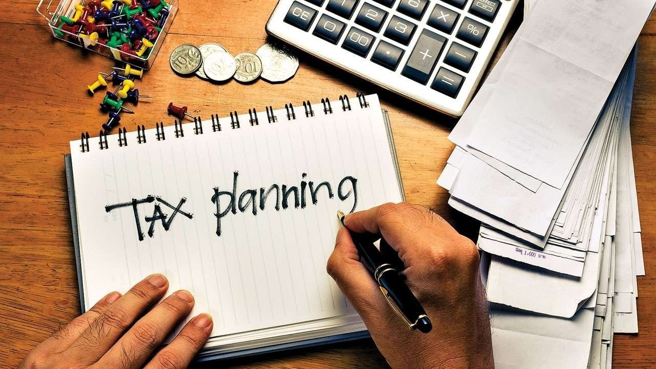 Notebook with “Tax planning” written by hand beside a calculator, coins, and paperwork, representing why businesses in London, Ontario should begin tax strategy and CRA planning immediately after filing season.