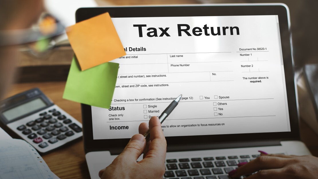 Laptop screen displaying a tax return form with calculator, notes, and pen, representing the review of 2025 tax returns to identify deductions, CRA adjustments, and tax planning opportunities in Ontario, Canada.