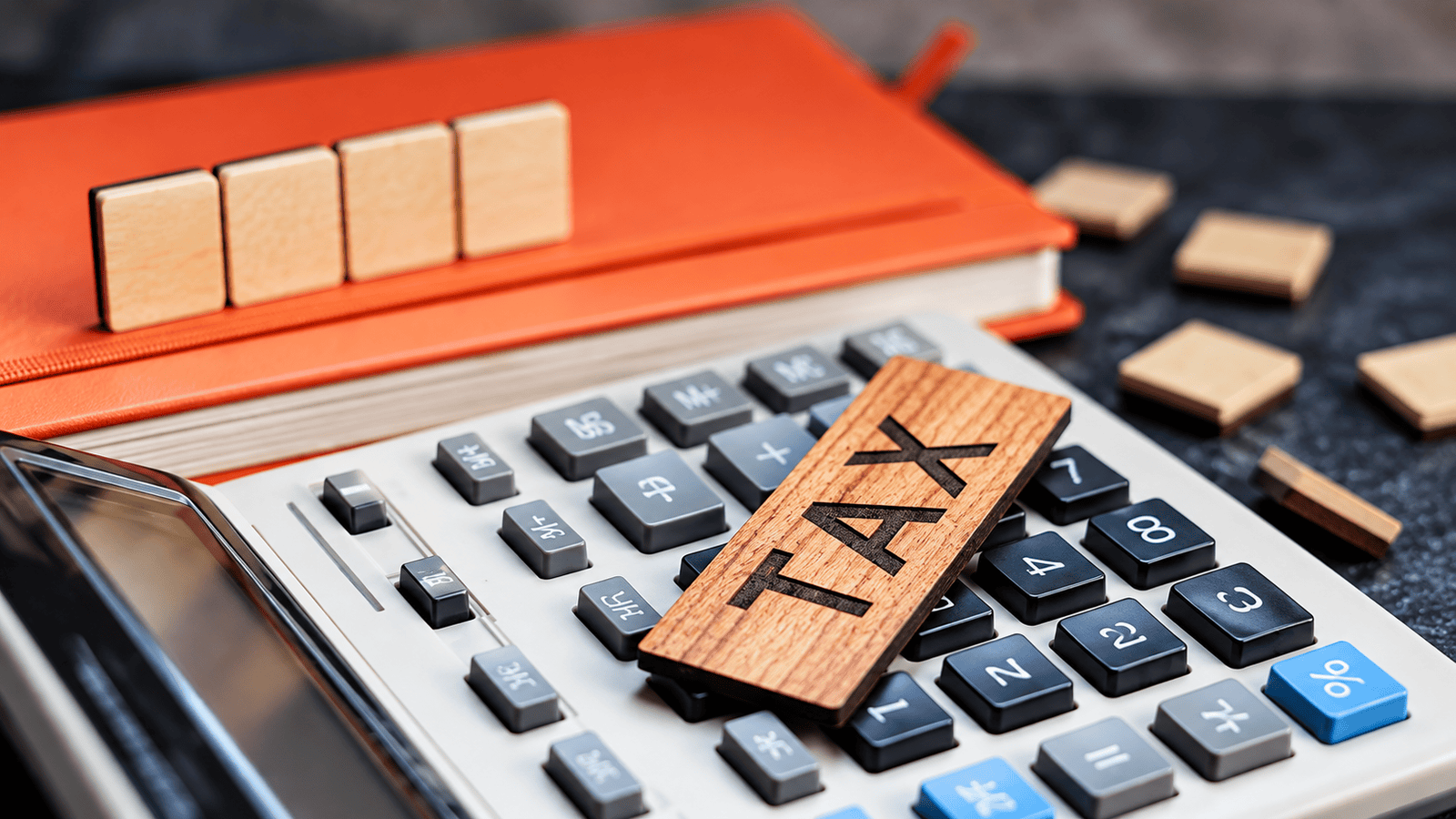Calculator with a wooden ‘TAX’ block beside a business planner, representing the importance of choosing the right fiscal year-end when setting up a new Canadian corporation.