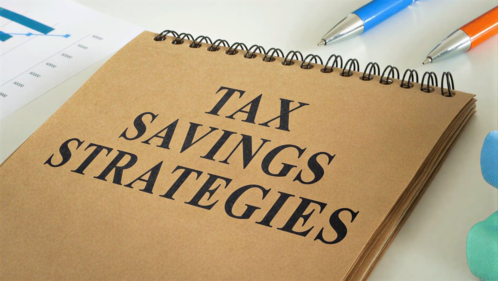 Notebook displaying “Tax Savings Strategies” with pens and financial charts, representing tax reduction opportunities, deductions, and strategic planning for businesses in Ontario, Canada.